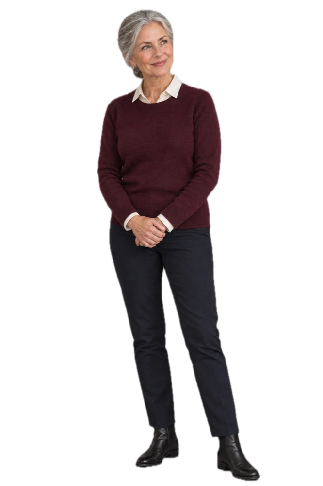 Ingrid, sixty-two, in a burgundy sweater over a cream collar, hands clasped, looking toward her page